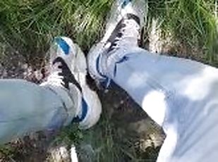 Young guy in sneakers and blue jeans smoke in the forest